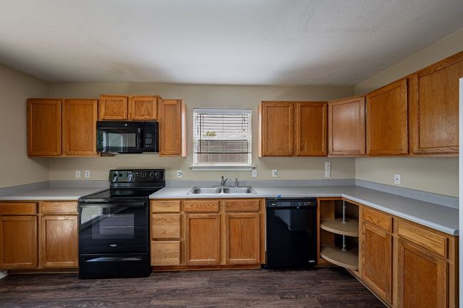 Kitchen with black appliances, a sink, dark wood-style flooring, and light countertops | Image 11