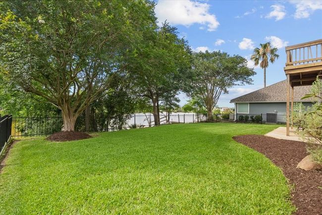 Welcome to your spacious backyard with lush green grass, a balcony and patio area, surrounded by trees and perfect for outdoor gatherings and relaxing. | Image 38