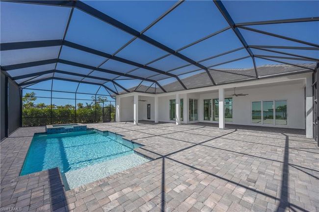 View of swimming pool featuring a ceiling fan, a pool with connected hot tub, glass enclosure, and a patio area | Image 25