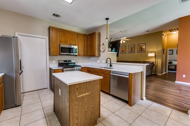 Kitchen featuring stainless steel appliances, a sink, a peninsula, open floor plan, and ceiling fan | Image 10