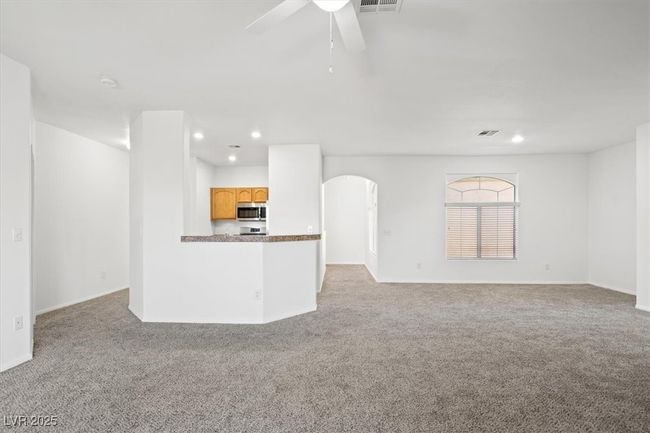 Unfurnished living room featuring visible vents, a ceiling fan, recessed lighting, arched walkways, and carpet floors | Image 8