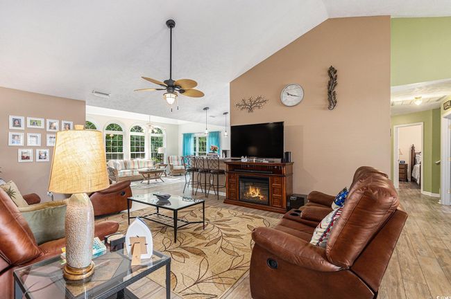 Living room with light wood-style floors, ceiling fan, high vaulted ceiling, and baseboards | Image 13