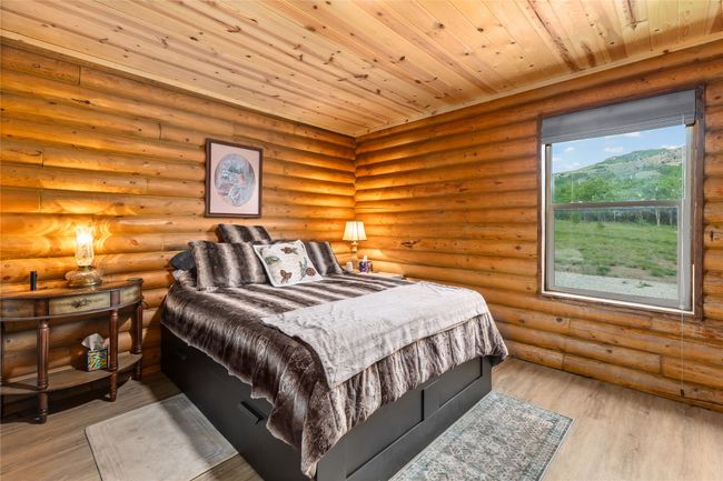 Bedroom with wood finished floors, log walls, and wooden ceiling | Image 15