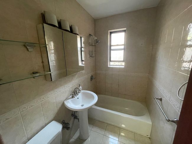 Full bath with toilet, tile patterned flooring, washtub / shower combination, and tile walls | Image 13