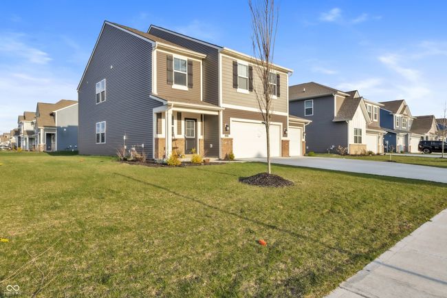 view of front of house featuring a garage, a residential view, concrete driveway, and a front yard | Image 36