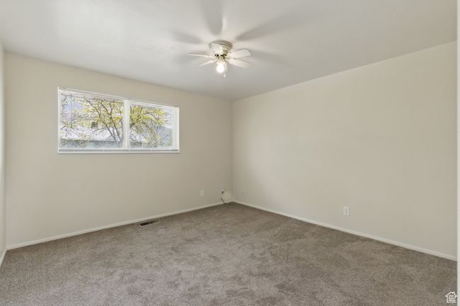 Empty room with carpet floors, visible vents, baseboards, and ceiling fan | Image 12