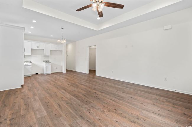 Unfurnished living room with recessed lighting, a ceiling fan, dark wood-style flooring, baseboards, and a chandelier | Image 7