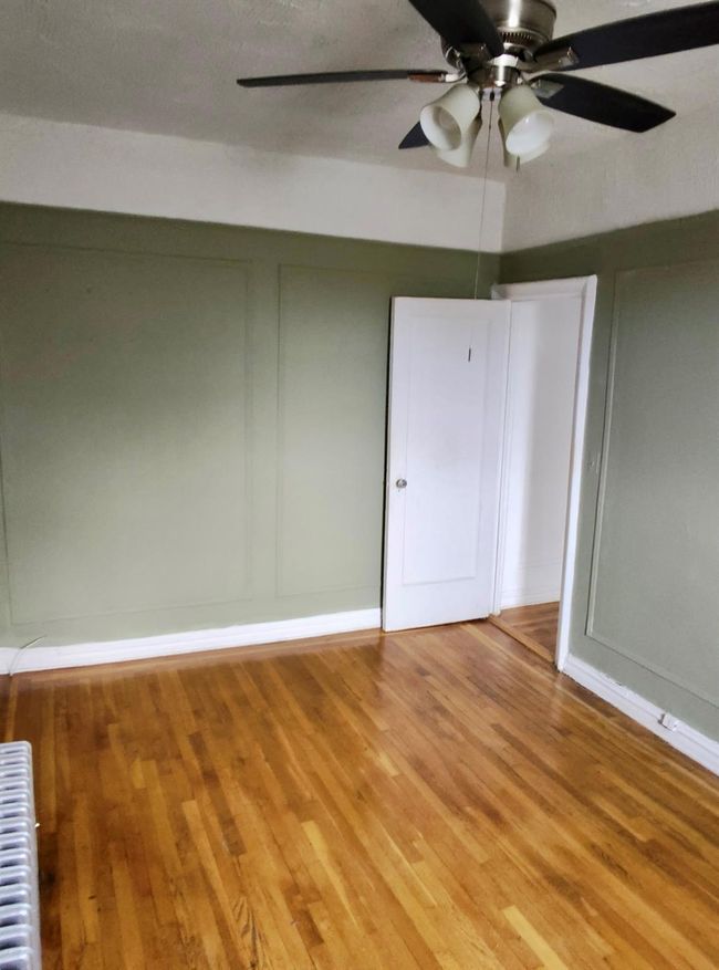 Spare room featuring a decorative wall, radiator heating unit, and wood finished floors | Image 19