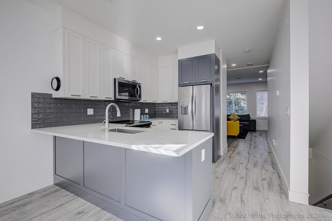 Kitchen with stainless steel appliances, a peninsula, light countertops, decorative backsplash, and recessed lighting | Image 5