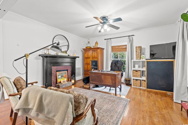 Office space featuring ceiling fan, ornamental molding, a fireplace, and wood finished floors | Image 13