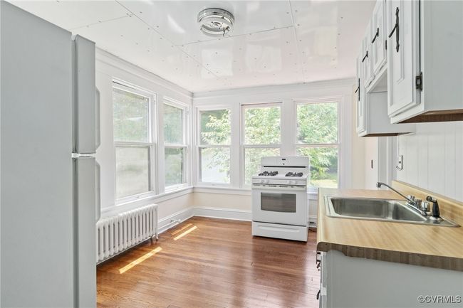 Kitchen featuring radiator heating unit, white appliances, a sink, and wood finished​​‌​​​​‌​​‌‌​‌‌​​​‌‌​​‌‌​‌​​​​​‌ floors | Image 38