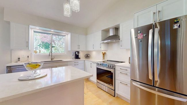 Kitchen featuring lofted ceiling, light countertops, a sink, and appliances with stainless steel finishes | Image 4