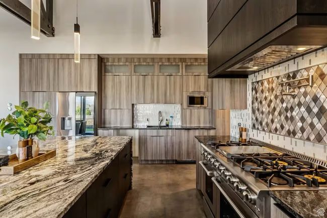 Kitchen featuring a sink, appliances with stainless steel finishes, wall chimney exhaust hood, dark stone countertops, and modern cabinets | Image 5