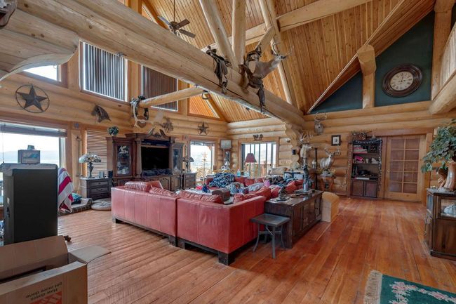 Living room featuring high vaulted ceiling, log walls, a ceiling fan, hardwood / wood-style flooring, and wood ceiling with exposed beams | Image 26