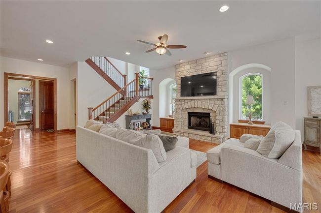 Living area featuring ceiling fan, a fireplace, stairway, recessed lighting, and light wood-style floors | Image 12