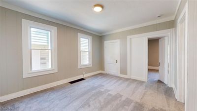 Unfurnished bedroom with light colored carpet and crown molding | Image 2