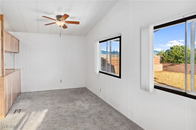 Carpeted living room with a ceiling fan, visible vents, and vaulted ceiling | Image 9