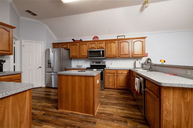 Kitchen with stainless steel appliances, vaulted ceiling, visible vents, ornamental molding, and a sink | Image 17