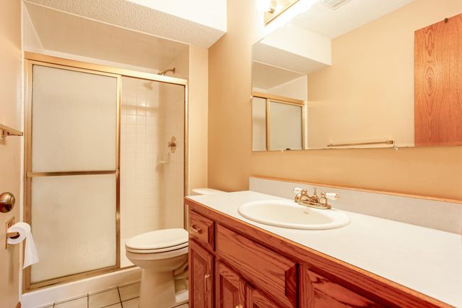 Lower-level ¾ bath with walk-in shower, rich wood cabinetry, and neutral tile—clean and functional with classic finishes. | Image 27