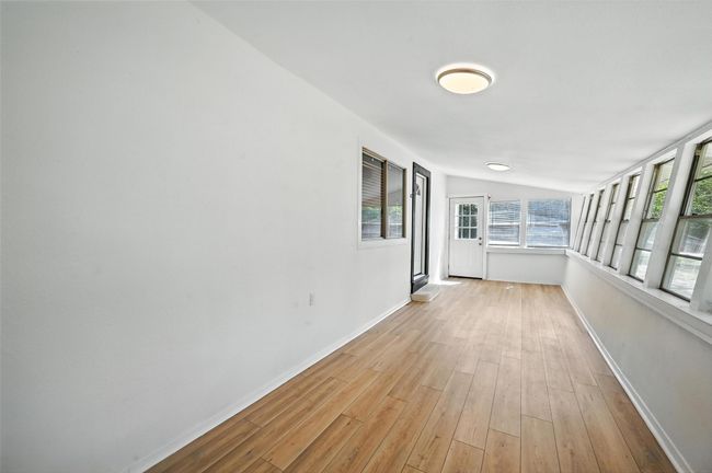 Unfurnished sunroom with wood finished floors and lofted ceiling | Image 5
