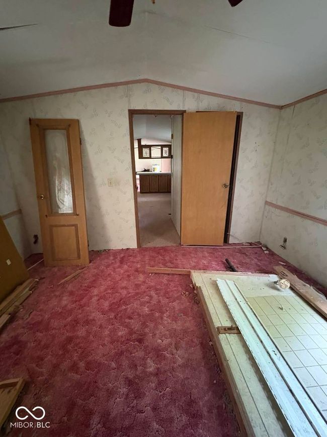 empty room with lofted ceiling, ceiling fan, wallpapered walls, ornamental molding, and light colored carpet | Image 8