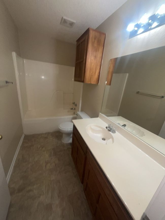 Full bath featuring toilet, vanity, baseboards, visible vents, and shower / bath combination | Image 11