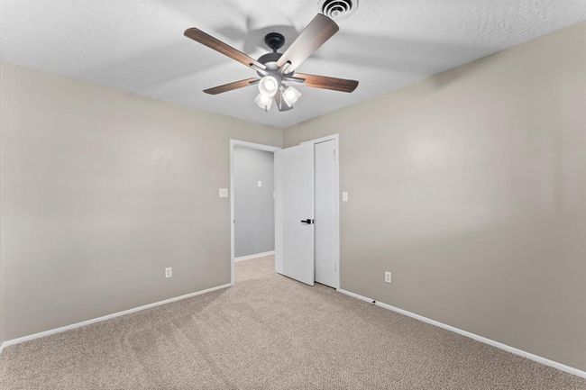 This room features neutral walls and carpet, providing a cozy and versatile space. It includes a ceiling fan with lights, offering comfort and illumination. | Image 21