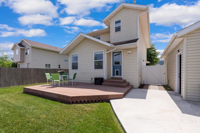 Back of house with a vinyl gate, a Trex deck, outdoor dining area, entry steps, and a patio area | Image 36