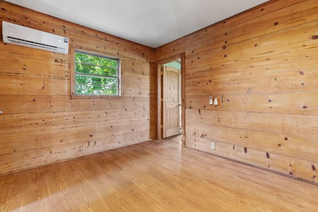 Empty room featuring a wall unit AC, wood walls, and wood finished floors | Image 24