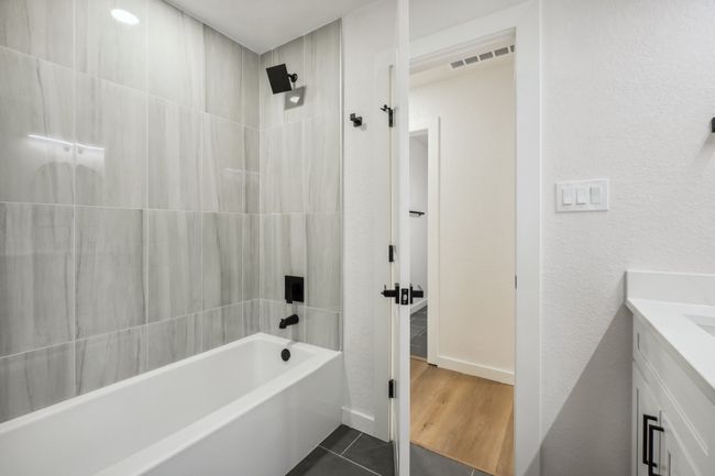 Full bath with bathtub / shower combination, vanity, tile patterned floors, and baseboards | Image 31