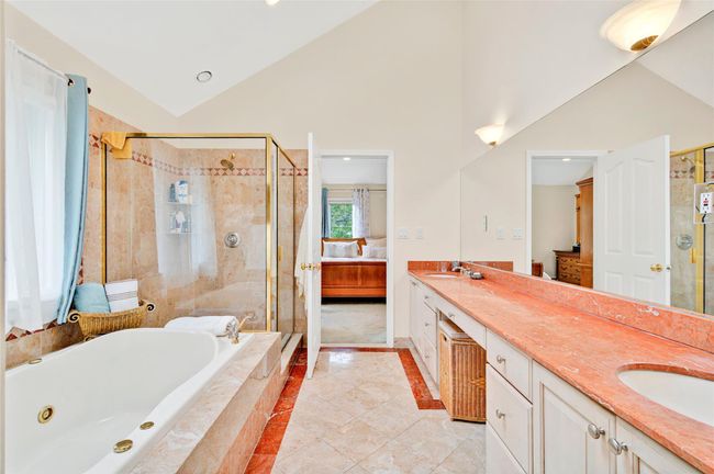 Full bathroom featuring connected bathroom, a stall shower, double vanity, a tub with jets, and high vaulted ceiling | Image 29