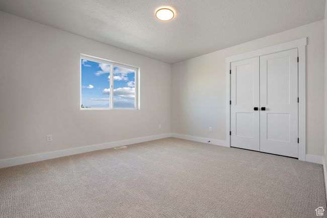 Unfurnished bedroom featuring light colored carpet, a closet, and a textured ceiling | Image 25