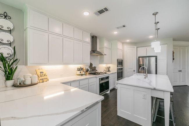 Kitchen with tasteful backsplash, dark wood-style flooring, white cabinets, stainless steel appliances, and recessed lighting | Image 7