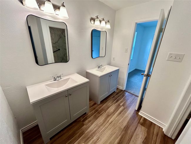 Bathroom with wood finished floors, two vanities, and baseboards | Image 17