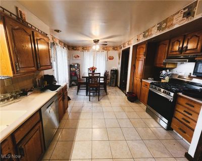 Kitchen with light tile patterned floors, appliances with stainless steel finishes, backsplash, ceiling fan, and sink | Image 2