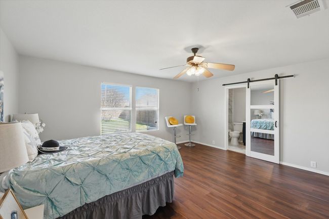 Bedroom with a barn door, wood finished floors, a ceiling fan, and ensuite bathroom | Image 17