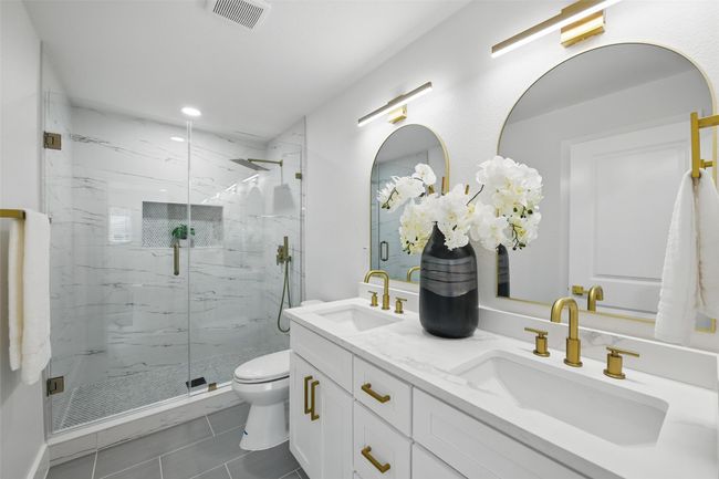 Bathroom with toilet, a marble finish shower, double vanity, tile patterned flooring, and recessed lighting | Image 22