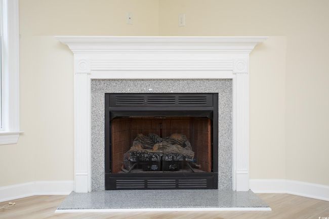 Detailed view of a fireplace with raised hearth, wood finished floors, and baseboards | Image 11