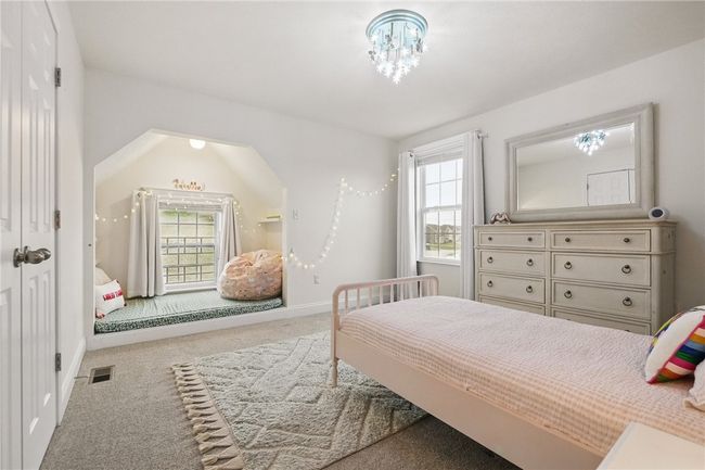 Delightful bedroom with soft neutral tones, plush carpeting, and a large window providing plenty of natural light. A charming built-in nook adds a cozy and fun hideaway perfect for reading, relaxing, or imaginative play. Double closet | Image 26