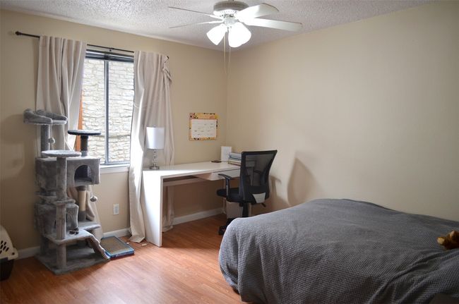 Bedroom with multiple windows, light wood finished floors, a textured ceiling, and a ceiling fan | Image 9