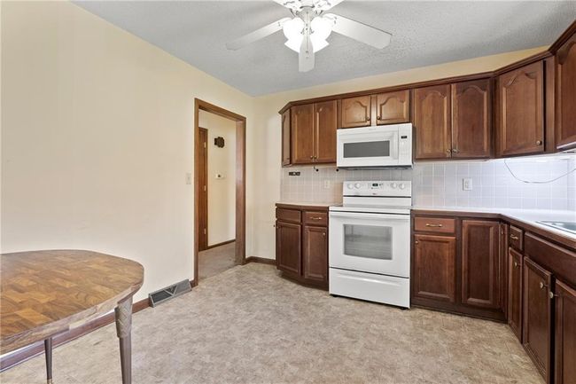Kitchen featuring white appliances, light floors, ceiling fan, light countertops, and tasteful backsplash | Image 12
