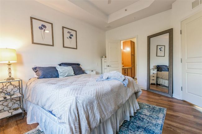 Bedroom featuring visible vents, baseboards, a raised ceiling, and wood finished floors | Image 10