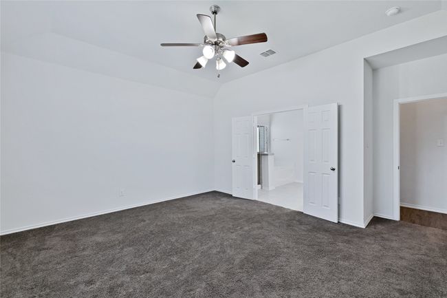 Unfurnished bedroom with dark carpet, ceiling fan, and vaulted ceiling | Image 12