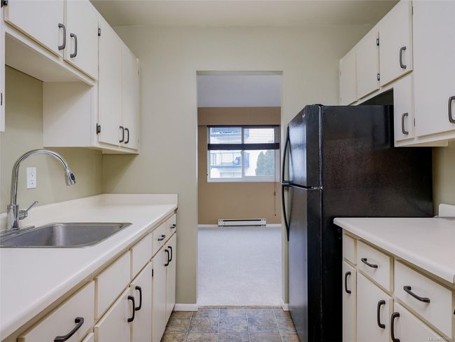 Kitchen featuring a baseboard heating unit, light countertops, and white cabinets | Image 10