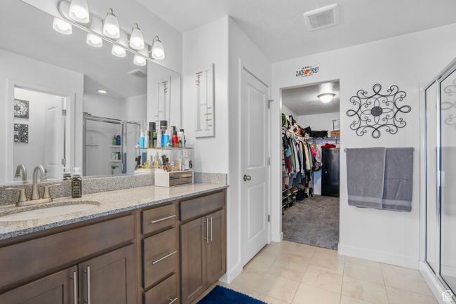 Full bathroom featuring visible vents, tile patterned flooring, a shower stall, vanity, and a walk in closet | Image 15