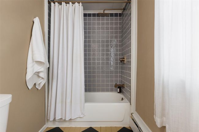 Bathroom featuring baseboard heating, toilet, and shower / bath combo with shower curtain | Image 15