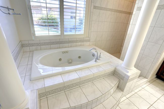 Full bathroom with ornate columns and a tub with jets | Image 13