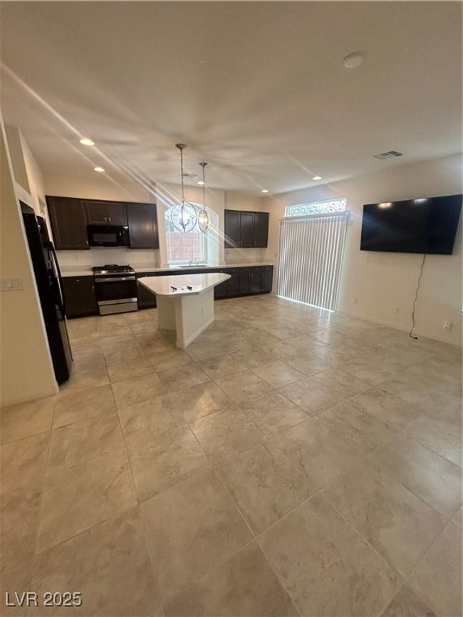 Kitchen featuring range, refrigerator, light countertops, open floor plan, and a kitchen island | Image 6