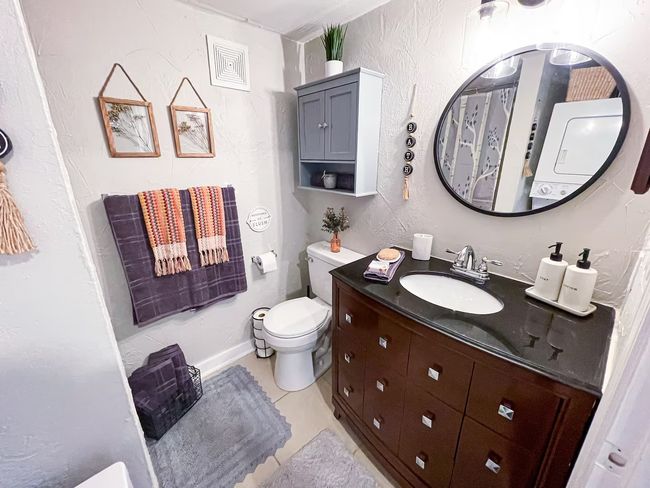 Bathroom with tile patterned floors, toilet, vanity, and a textured wall | Image 14