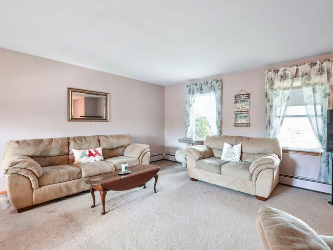 Carpeted living room with a wealth of natural light and baseboard heating | Image 8